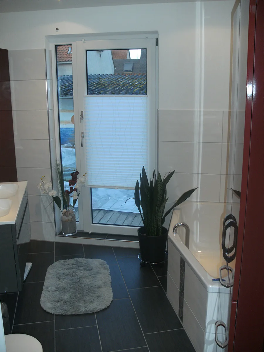 Saniertes Bad mit Wanne und dunklem Fliesenboden (Ortner-Projekt)
